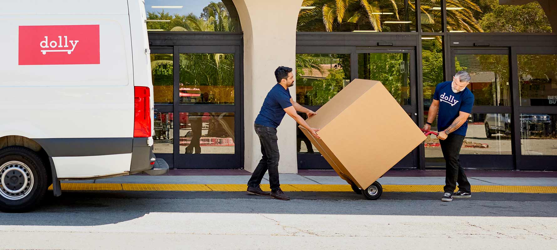 2 Dolly Helpers moving a box outside of a store